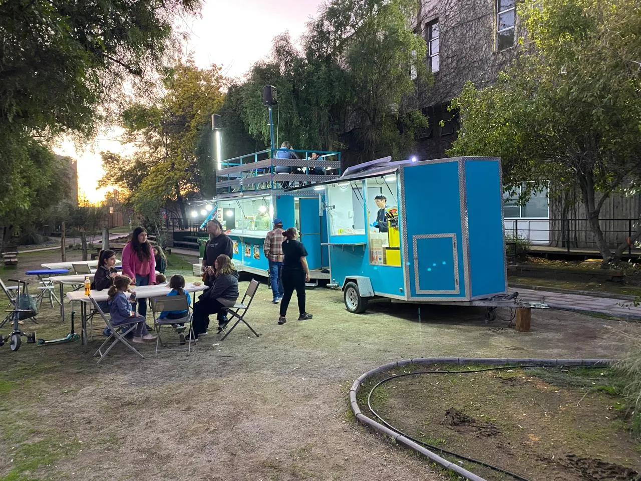 Clientes comiendo en las mesas junto al carro durante el día