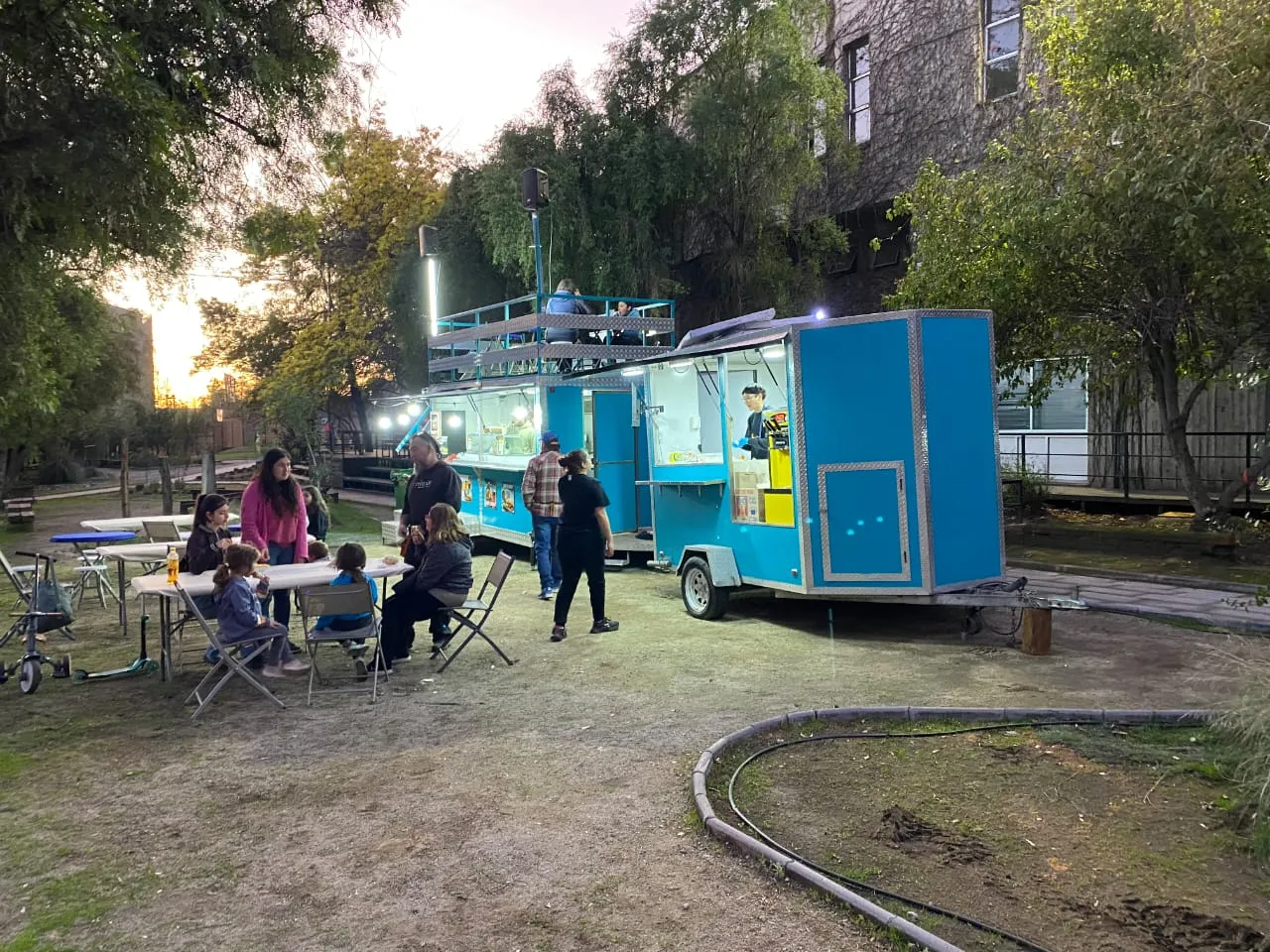 Mesas llenas de gente junto al carro al atardecer