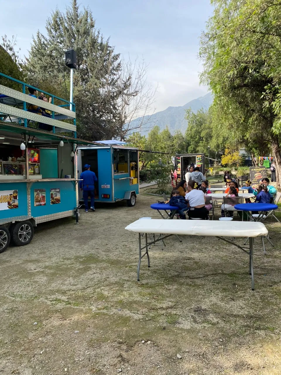 Clientes comiendo junto al carro con la cordillera de fondo