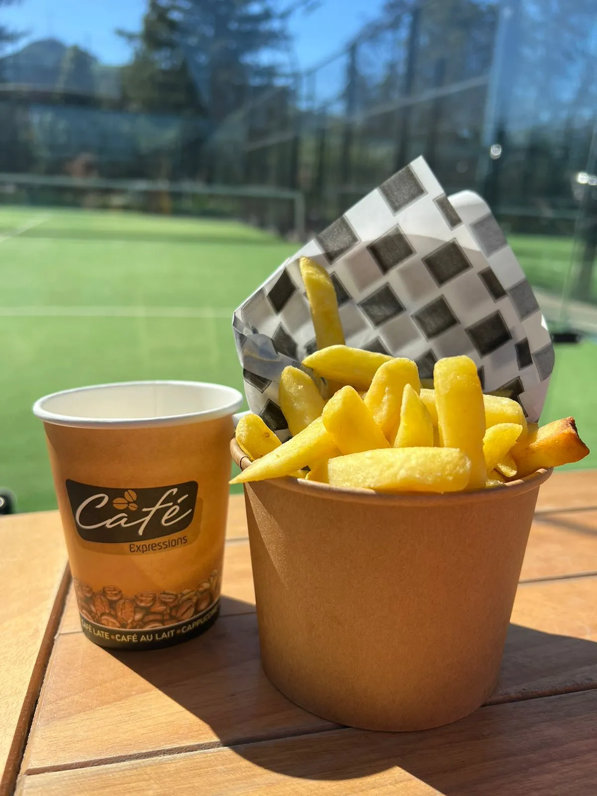 Café en vaso de papel junto a papas fritas